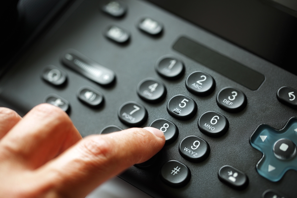 Person dialing a VoIP phone keypad, showing modern business communication and cloud-based voice technology in use.